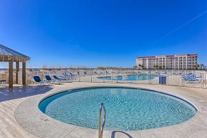 a swimming pool with chairs and a building in the background at Sugar Beach in Gulf Shores