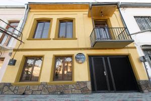 a yellow building with a balcony on top of it at Anna's Guest House in Gori