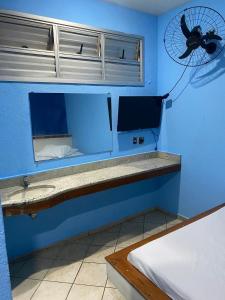 a room with a blue wall with a fan at Hotel Angely in Belo Horizonte