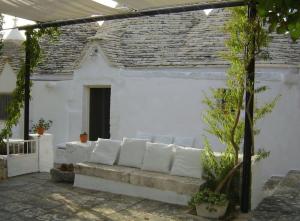 Trulli-Mestandrea al poggio piscina uso esclusivo في نوتشي: أريكة بيضاء أمام مبنى أبيض