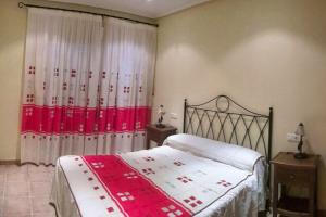 um quarto com uma cama com um cobertor vermelho e branco em 3 bedrooms villa with shared pool terrace and wifi at Vera 3 km away from the beach em Vera