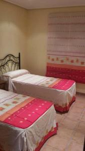 três camas num quarto com lençóis cor-de-rosa e brancos em 3 bedrooms villa with shared pool terrace and wifi at Vera 3 km away from the beach em Vera