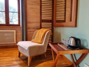 a chair and a table in a room with a coffee table at Chambre familiale au cœur de la nature avec jardin et piscine privée, idéale pour explorer le Loiret - FR-1-590-265 in Vitry-aux-Loges