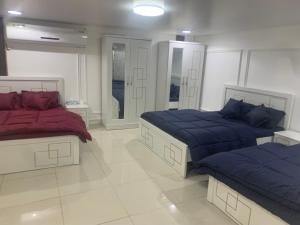 een slaapkamer met 2 bedden met blauwe en rode lakens bij Noor Farm Stay 5BHK in Khor Fakkan