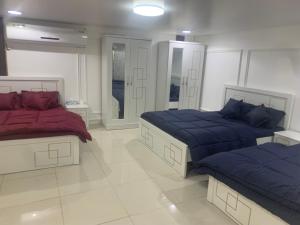 a bedroom with two beds with blue and red sheets at Noor Farm Stay 5BHK in Khor Fakkan +34 photos