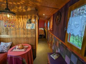 ein Zugzimmer mit einem Tisch und einem Fenster in der Unterkunft Séjour insolite en roulotte cosy avec tout confort près d'Épinal - FR-1-589-459 in Sercoeur