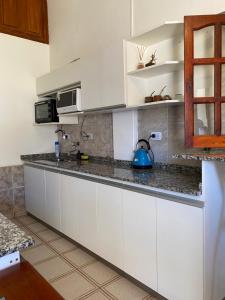- une cuisine avec des placards blancs et une bouilloire bleue sur le comptoir dans l'établissement Miel, à Tinogasta