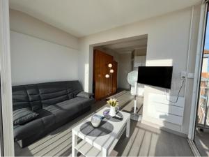 ein Wohnzimmer mit einem schwarzen Sofa und einem TV in der Unterkunft Studio magnifique vue mer et port in Valras-Plage