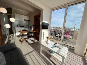 ein Wohnzimmer mit einem Sofa, einem Tisch und einem Fenster in der Unterkunft Studio magnifique vue mer et port in Valras-Plage