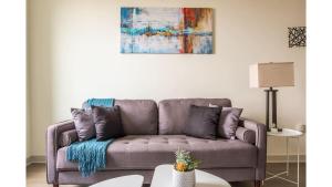 a couch in a living room with a painting on the wall at Stunning Nulu 1BR CozySuites 03 in Louisville