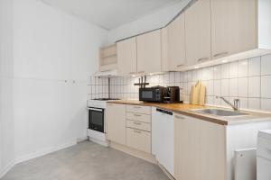 eine weiße Küche mit einer Spüle und einer Mikrowelle in der Unterkunft New Yorker 2 BR lejlighed tæt på Aalborg Centrum in Aalborg