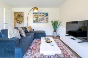 a living room with a blue couch and a table at Exquisite Apartment with Balcony, Free Parking, Fast WiFi, and Smart TV by Yoko Property in Milton Keynes