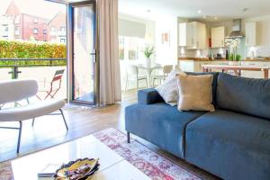 a living room with a blue couch and a kitchen at Exquisite Apartment with Balcony, Free Parking, Fast WiFi, and Smart TV by Yoko Property in Milton Keynes