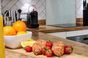 a cutting board with strawberries and croissants and a bowl of fruit at Exquisite Apartment with Balcony, Free Parking, Fast WiFi, and Smart TV by Yoko Property in Milton Keynes