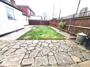 a backyard with a stone walkway and a fence at Beautiful quiet Victorian Bungalow heart of London in London