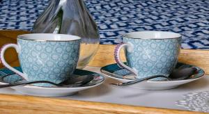 two cups and plates on a table with spoons at Paulas room. in Riga