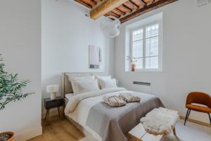 a white bedroom with a bed and a chair at Casa Lazzaro Contemporary Ground Floor Apartment in Lucca