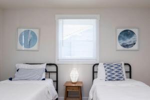two beds in a white room with a window at The Beach Vibe with Hot tub 8 min to the Beach in Virginia Beach