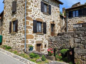 a stone house with black windows and a stone wall at Évasion au cœur de Polignac : Charme et confort à deux pas du Puy-en-Velay - FR-1-582-382 in Polignac