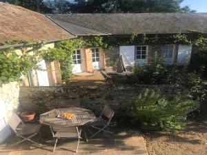 un tavolo e delle sedie davanti a una casa in pietra di Charmantes chambres d'hôtes avec piscine et coin cuisine près de l'abbaye de Solesmes - FR-1-410-404 a Solesmes