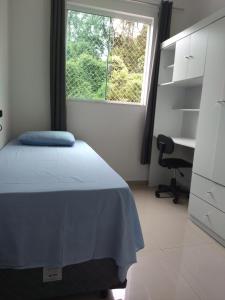 a bedroom with a bed and a desk and a window at APARTAMENTO INTEIRO BELA ARTE COSTA E SILVA, 2 QUARTOS in Joinville