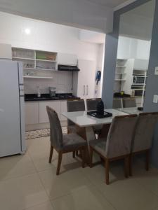 a kitchen with a table and chairs and a refrigerator at APARTAMENTO INTEIRO BELA ARTE COSTA E SILVA, 2 QUARTOS in Joinville