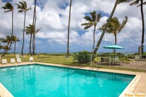 una piscina con palmeras y una sombrilla en Condo on Beach with AC, en Laie