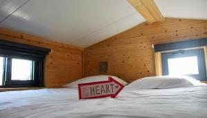 uma almofada de coração numa cama num quarto com paredes de madeira em Tiny house eco resort em Estevais