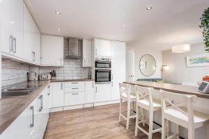 a kitchen with white cabinets and a bar with stools at 33 Lochgreen Avenue in Troon