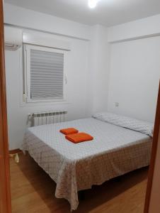 a bedroom with a bed with two orange towels on it at Habitación cerca centro d Madrid in Madrid