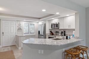a kitchen with white cabinets and a counter with two bar stools at Loggerhead 261 - Gorgeous Residence at Loggerhead Cay with Fantastic Amenities in Sanibel +16 photos