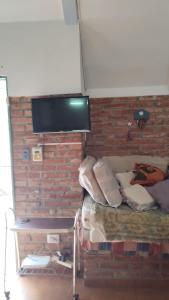 een kamer met een bakstenen muur, een bed en een televisie bij Paraíso de Mayú in San Antonio de Arredondo