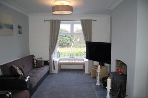 a living room with a couch and a television at Idris View Family Holiday Home in Tywyn