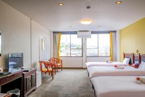 a hotel room with four beds and a television at 双龍居ホテル in Miki