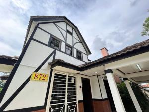 a white house with a black and white facade at Private Pool Villa Lot 872 - Fong Homestay in Kampong Alor Gajah
