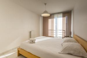 a bedroom with a large white bed with a window at Terrasse blanche - Premiere conciergerie in Montpellier