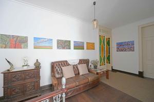 a living room with a couch and paintings on the wall at Matriz Guest House in Portel
