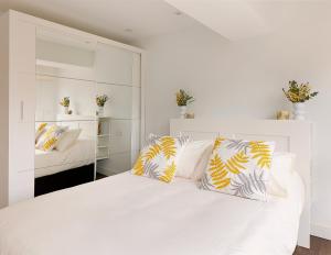 ein Schlafzimmer mit einem weißen Bett mit gelben und weißen Kissen in der Unterkunft Playa de San Lorenzo in Gijón