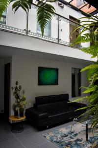 a black couch in a living room with a green painting at Hotel DC Feria in Bogotá