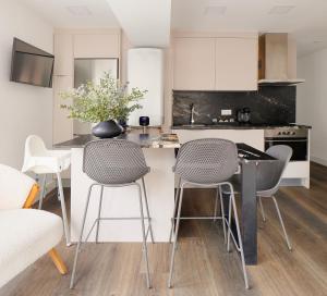 a kitchen with white cabinets and a counter with chairs at Playa de San Lorenzo in Gijón