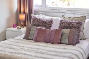 un letto con un sacco di cuscini sopra di Cosford House - 3BR House in a Kenton