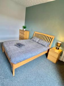a bedroom with a wooden bed and a night stand at Brooklyn Place by SG Property Group in Crewe