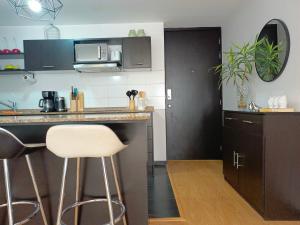 a kitchen with a counter and two bar stools at Downtown Quito - Balcony - Gym - Parking - 7thFLOOR in Quito