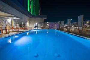a swimming pool at night with chairs and tables at Holiday Inn Glendale - Stadium & Ent Dist in Glendale