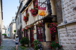 a woman walking down a street with flowers on a building at Ar Voudenn in Roz-Landrieux