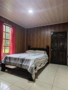 a bedroom with a bed with wooden walls and a window at Casa privada en el Bosque Nuboso Del Cocora in San Ramón