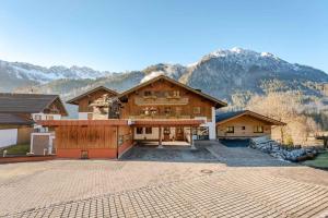 a large house with mountains in the background at Bergblick-Ferienwohnungen in Bad Hindelang