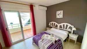 a bedroom with a bed with a table and a balcony at Apartamento Esmeralda VyB in Denia