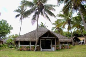a hut with a thatched roof and two palm trees at Vista Do Deus Resort in Ligogo