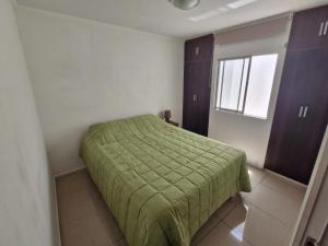 Un dormitorio con una cama verde y una ventana. en Esmeralda, en Antofagasta